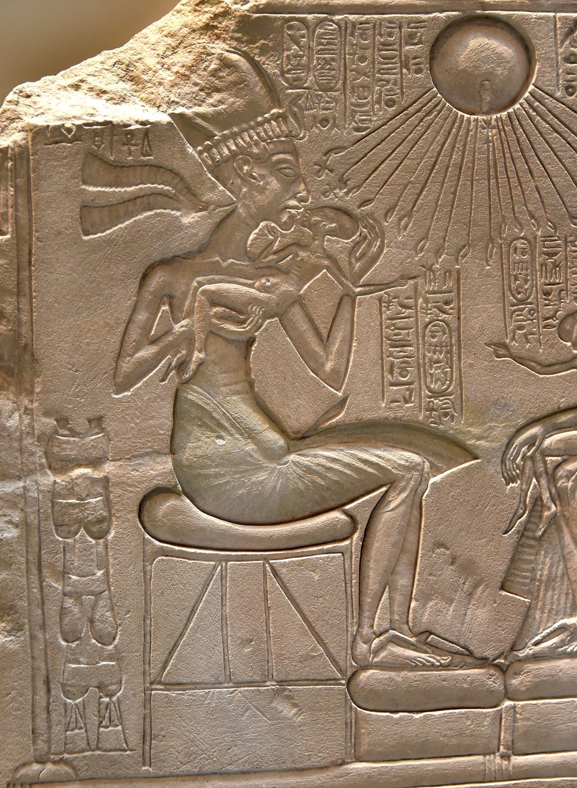 A stone relief of Akhenaten under the sun disc Aten, whose rays end in small hands.