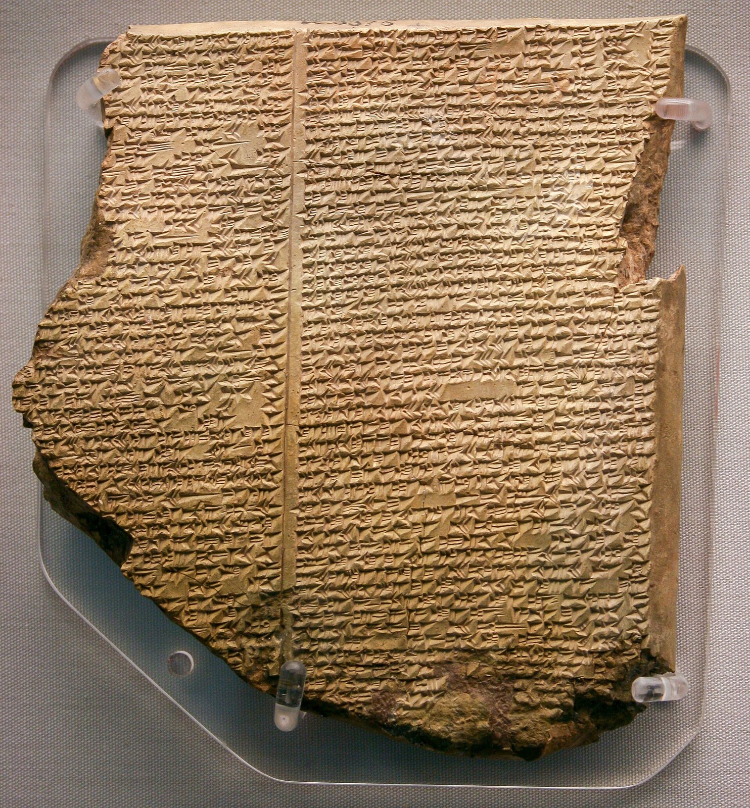 A broken clay tablet covered in dense cuneiform writing — the Flood Tablet of the Epic of Gilgamesh.
