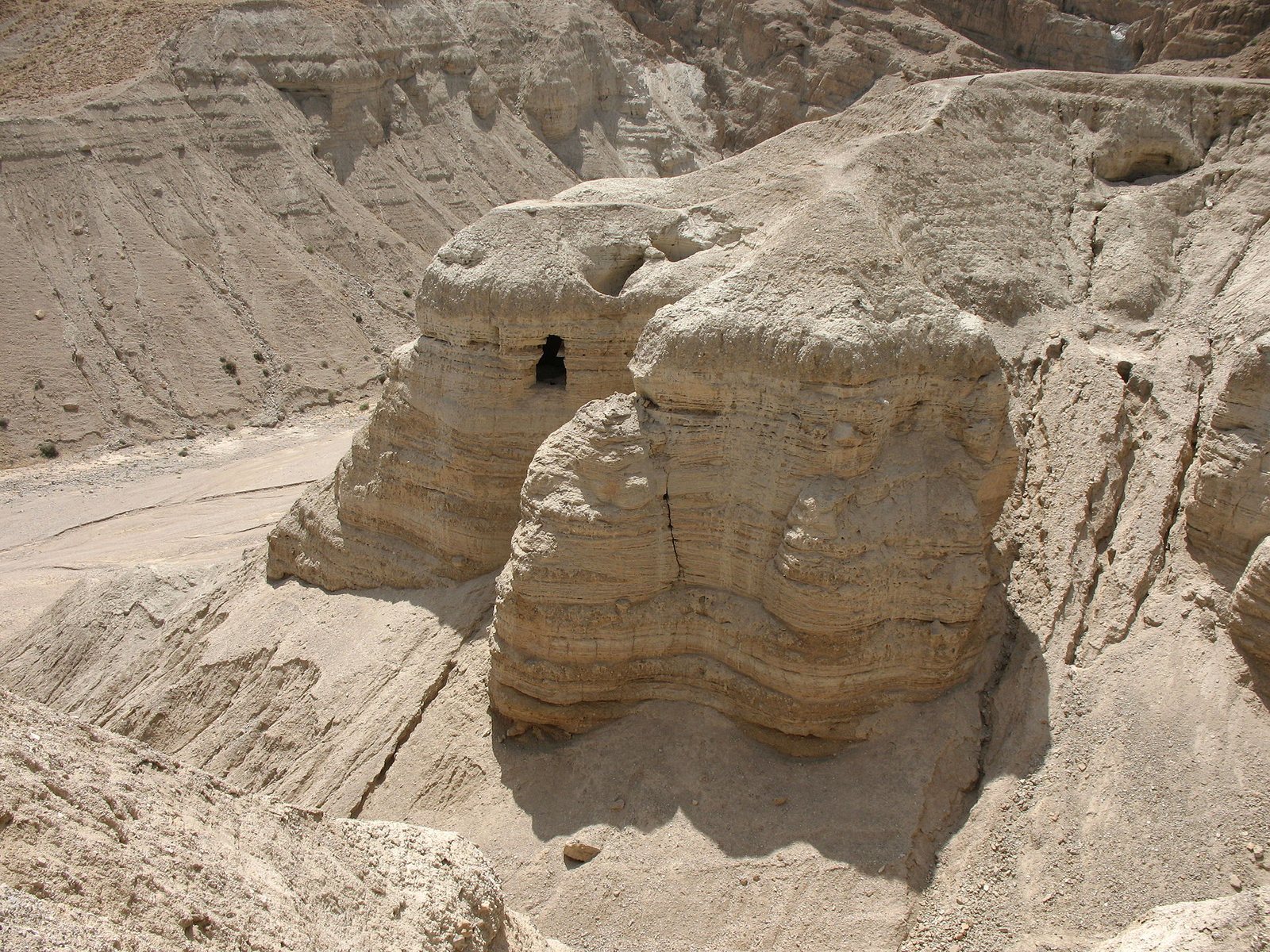 Desert cliffs at Qumran with dark cave openings.