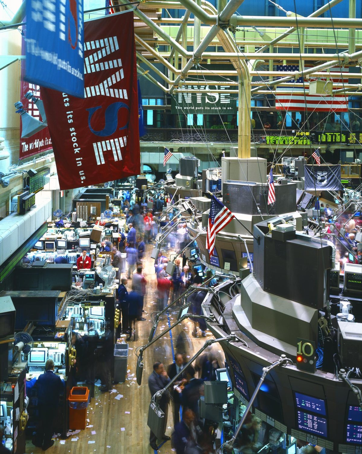 The New York Stock Exchange trading floor, with brokers working at terminals under large screens.