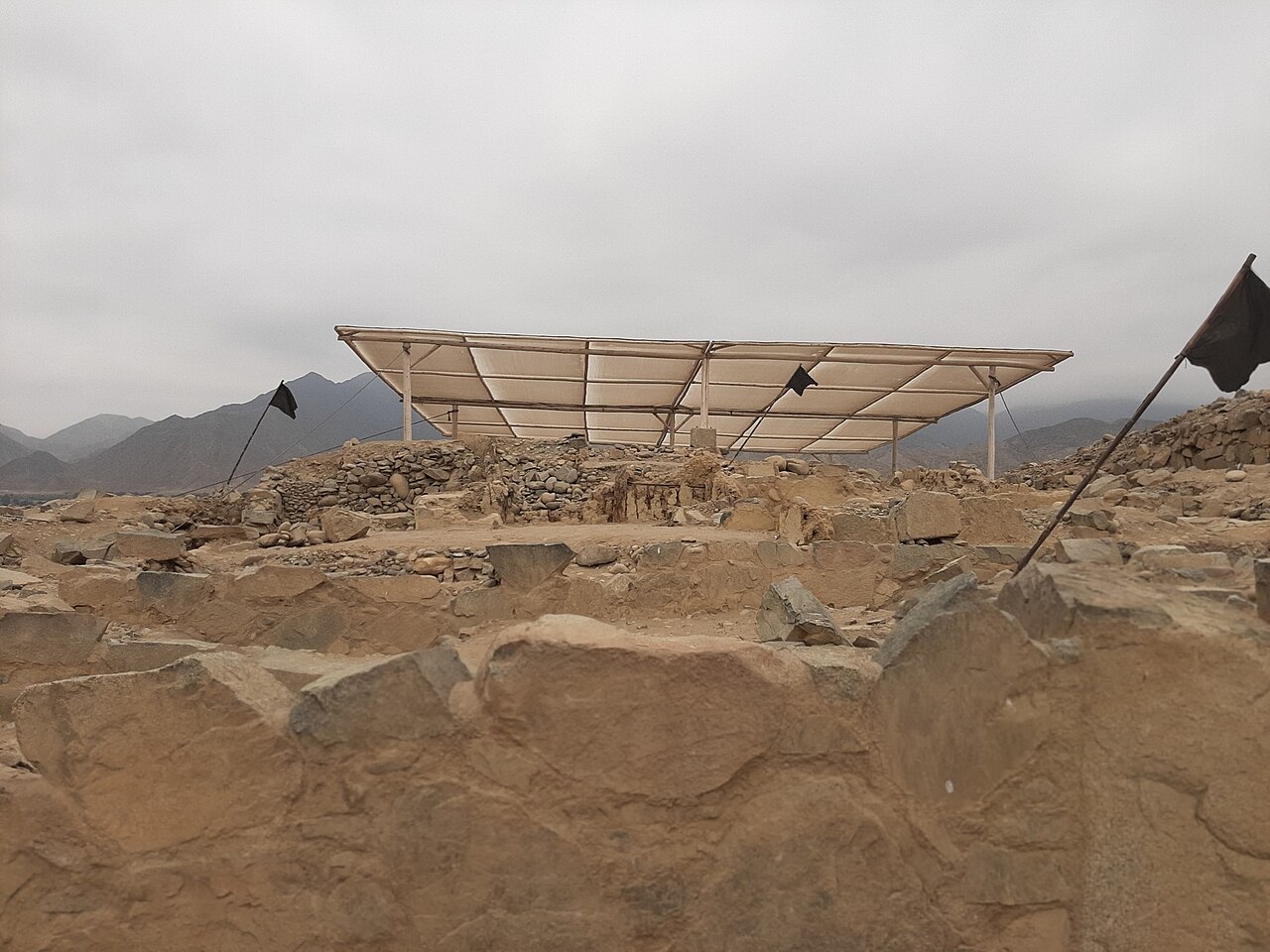 Excavated stone walls and platform structures at Caral in the Supe Valley, Peru, with the coastal range behind.