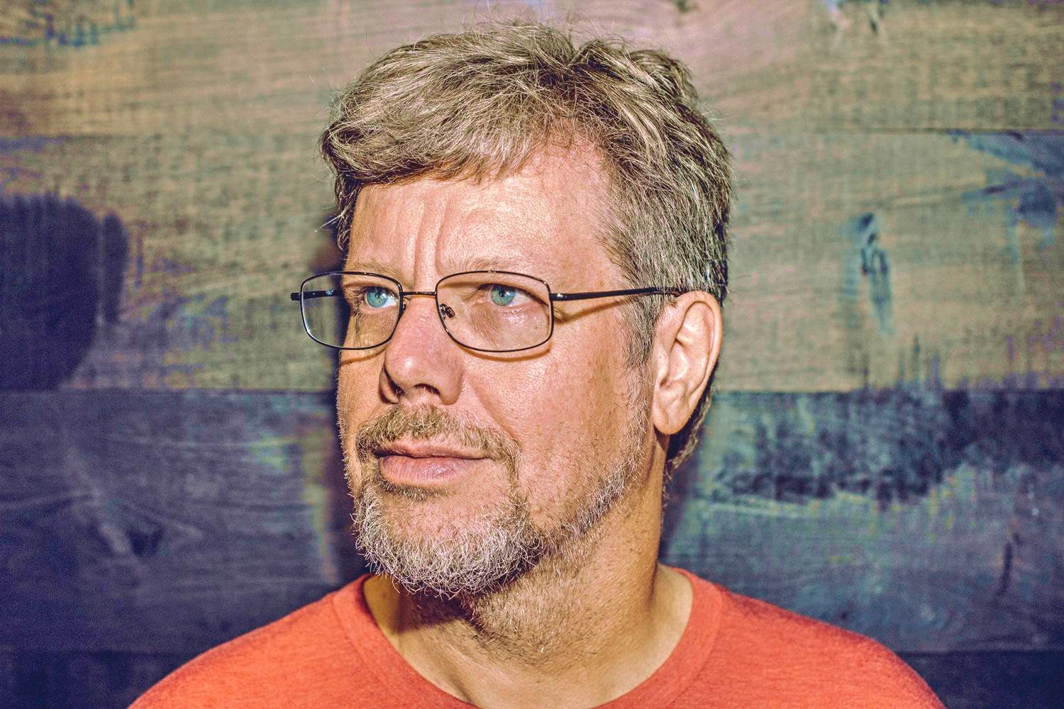 Portrait photograph of Guido van Rossum wearing glasses and a red shirt